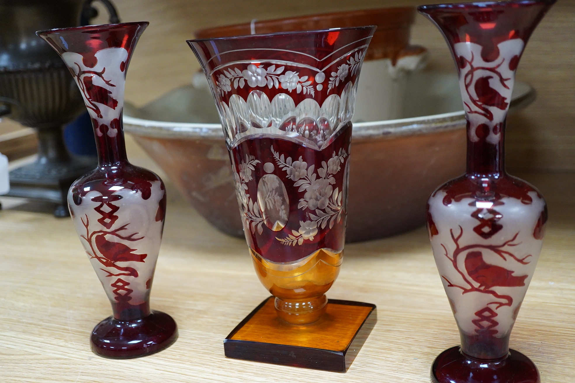 A Czechoslovakian red and amber cut glass square base vase, 21cm high and a pair of similar vases
